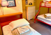 Dorm room with twin bed and a full/twin bunk, lots of hooks, three dressers and a partial clothes hanger nook at Wildflower Cabin #10 at Crow Wing Crest Lodge in Akeley, MN