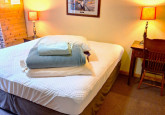 Lower main level king bed with solid platform frame, spacious bedroom with dresser, shelf and clothes hanger, plus a little writing desk and chair, additional rocker in Wildflower Cabin #10 at Crow Wing Crest Lodge in Akeley, MN